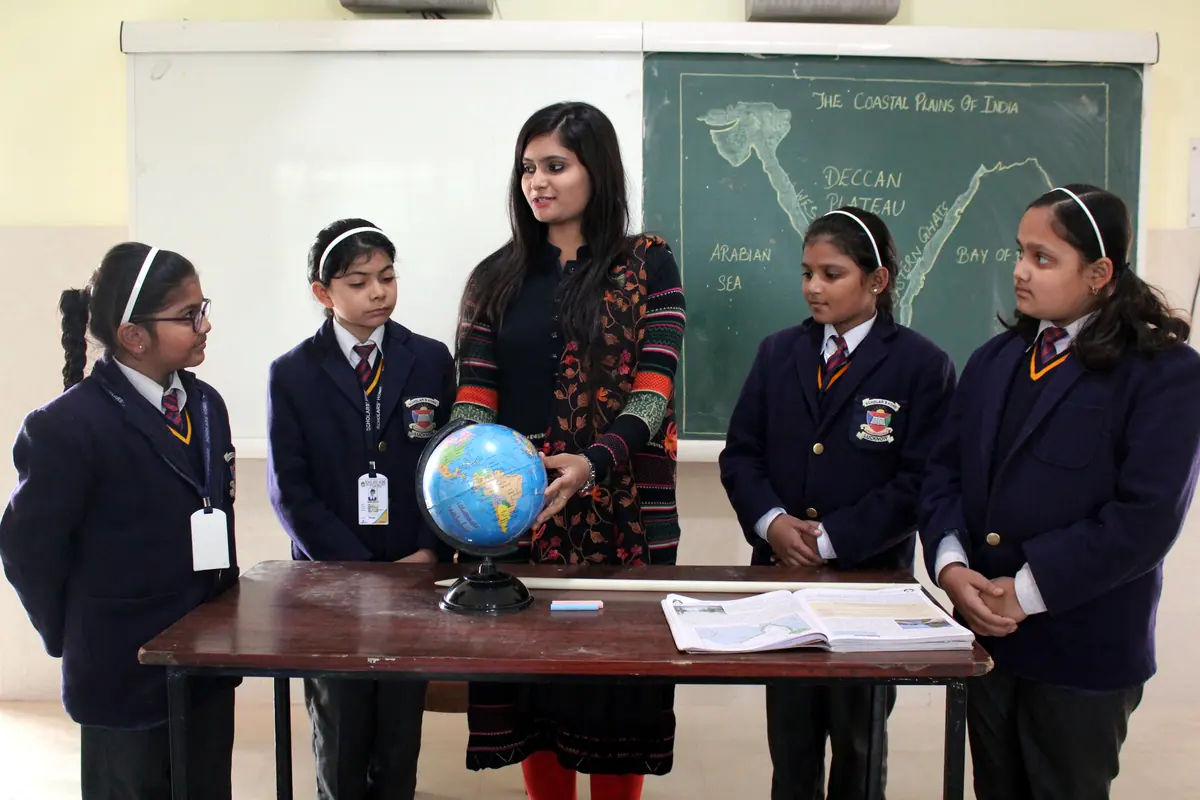 Middle-school students exploring a globe with their teacher